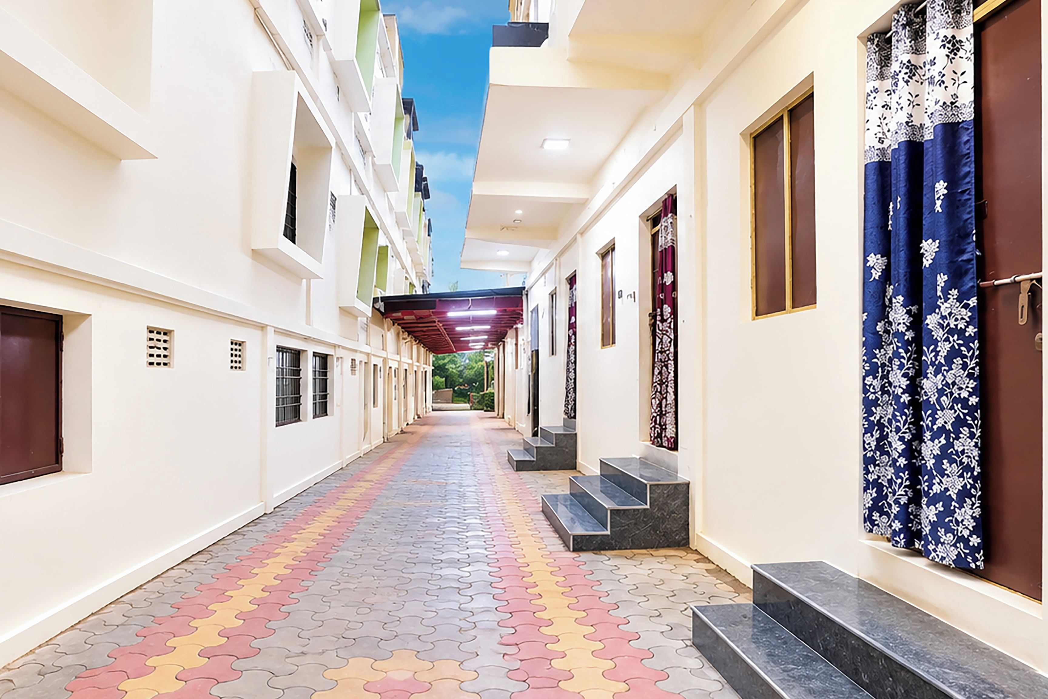 A corridor with a patterned floor, doors on the right, and a staircase leading to an upper level.