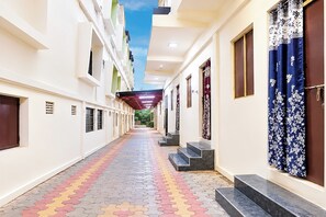 A corridor with a patterned floor, doors on the right, and a staircase leading to an upper level.
