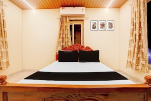 A hotel room with a bed, curtains, an air conditioning unit, and framed artwork on the wall. - Super Hotel O Kunjaban residency Barang (Cuttack)