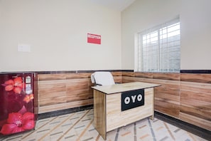 A reception desk with a sign that reads 'RECEPTION' and 'OYO' on a hotel lobby with patterned walls and a tiled floor. - Super Hotel O Kunjaban residency Barang (Cuttack)