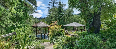 A garden with two gazebos, a stone pathway, and lush greenery.