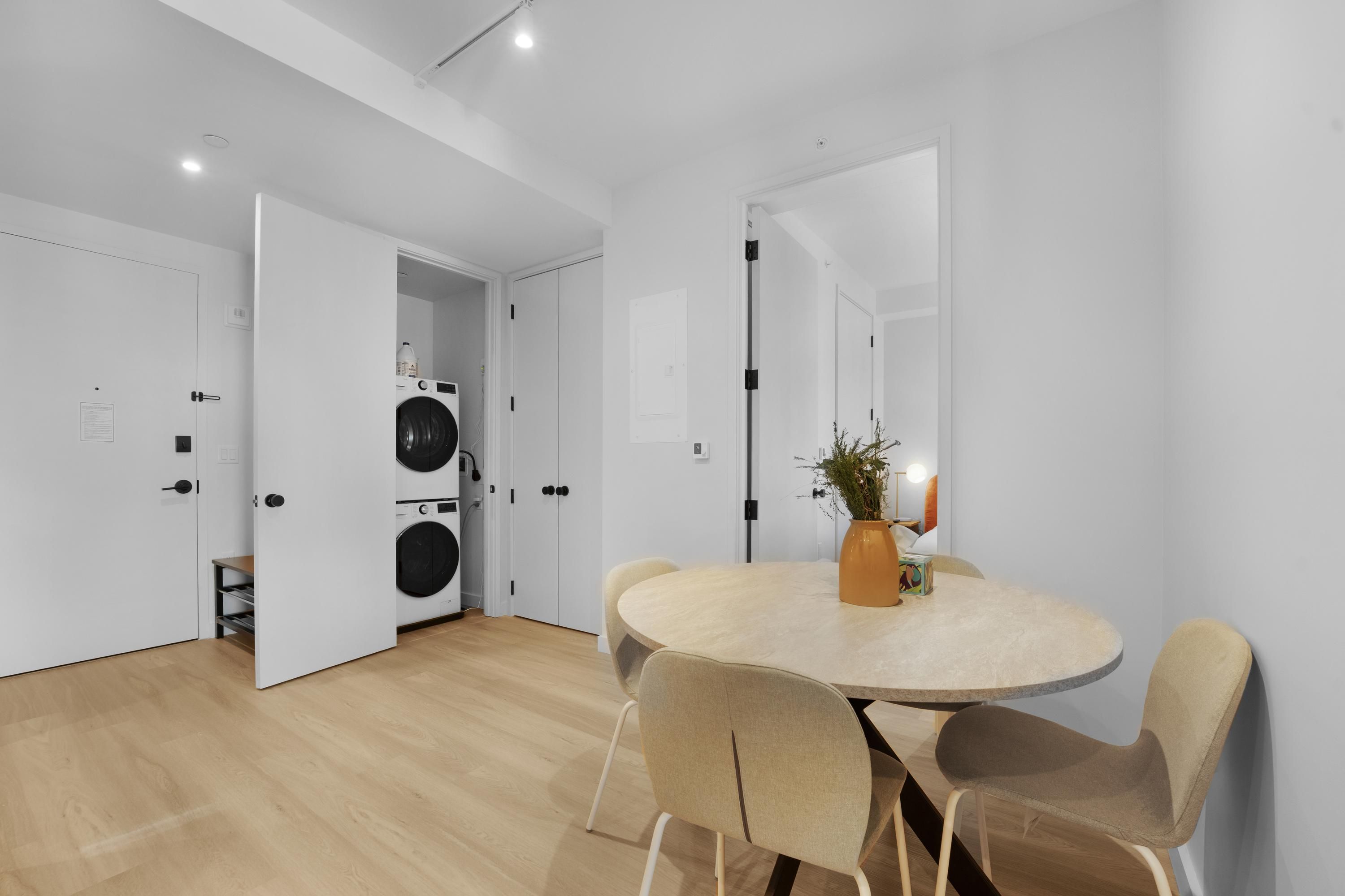 A modern kitchen with a built-in washing machine, a round dining table with chairs, and a large mirror on the wall.