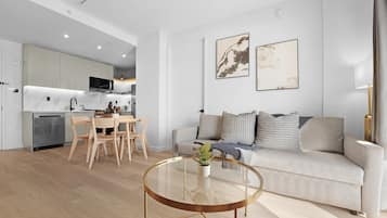 Un salon moderne comprenant un canapé, une table basse en verre et un coin repas avec des chaises et une table.