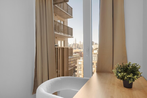 A modern room with a view of a cityscape through large windows, a wooden table, and a potted plant.