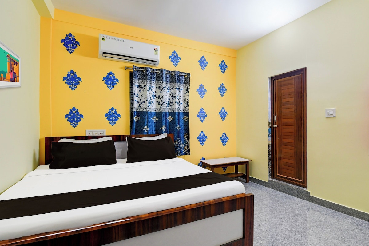 Ein Hotelzimmer mit einem Bett, einem Nachttisch, einer Klimaanlage, einer Tür und einer Wand mit dekorativen Mustern.