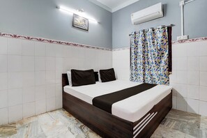 Habitación de hotel con una cama, aire acondicionado de pared y cortina estampada.