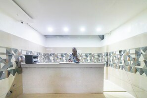 A reception area with a tiled wall, a reception desk, and a ceiling with recessed lighting. - Hotel O by OYO Prabir Residency Inn (Cuttack)