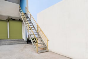 A stairway with a metal handrail leading to a building entrance. - Hotel O by OYO Sun Perfect Lodge (Cuttack)