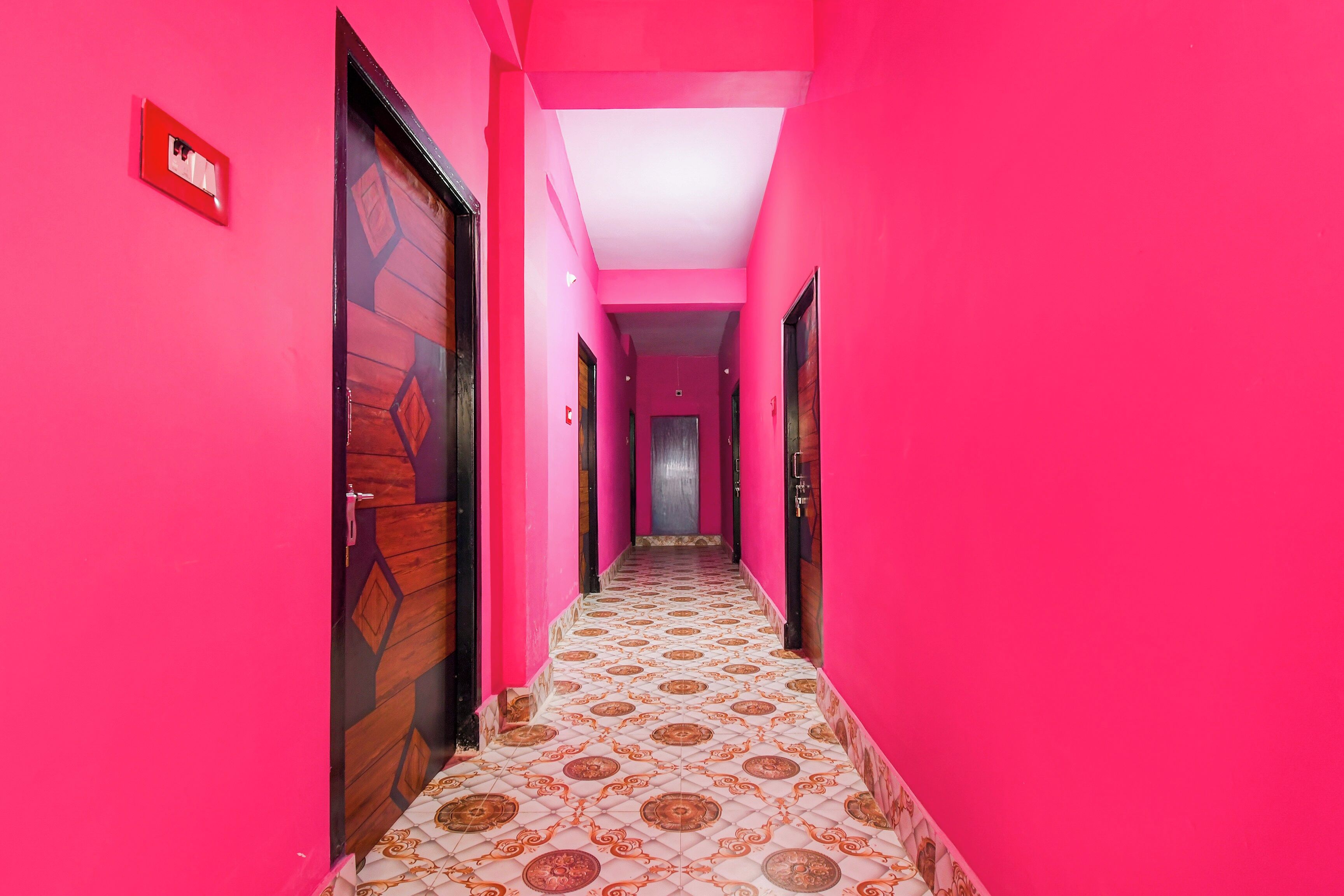 Un pasillo con paredes rosadas y baldosas de suelo estampadas.