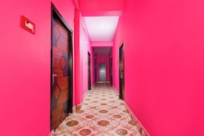 A hallway with pink walls and patterned floor tiles. - Hotel O by OYO Sun Perfect Lodge (Cuttack)