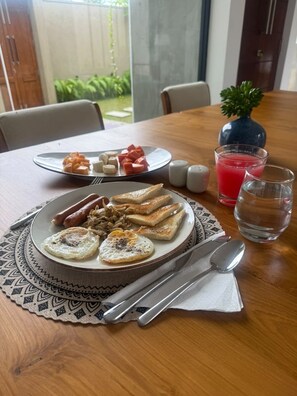 Une table mise pour le petit-déjeuner, avec des assiettes remplies de nourriture, des couverts et des verres.