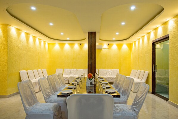 A conference room with a round table, white chairs, and a glass partition.