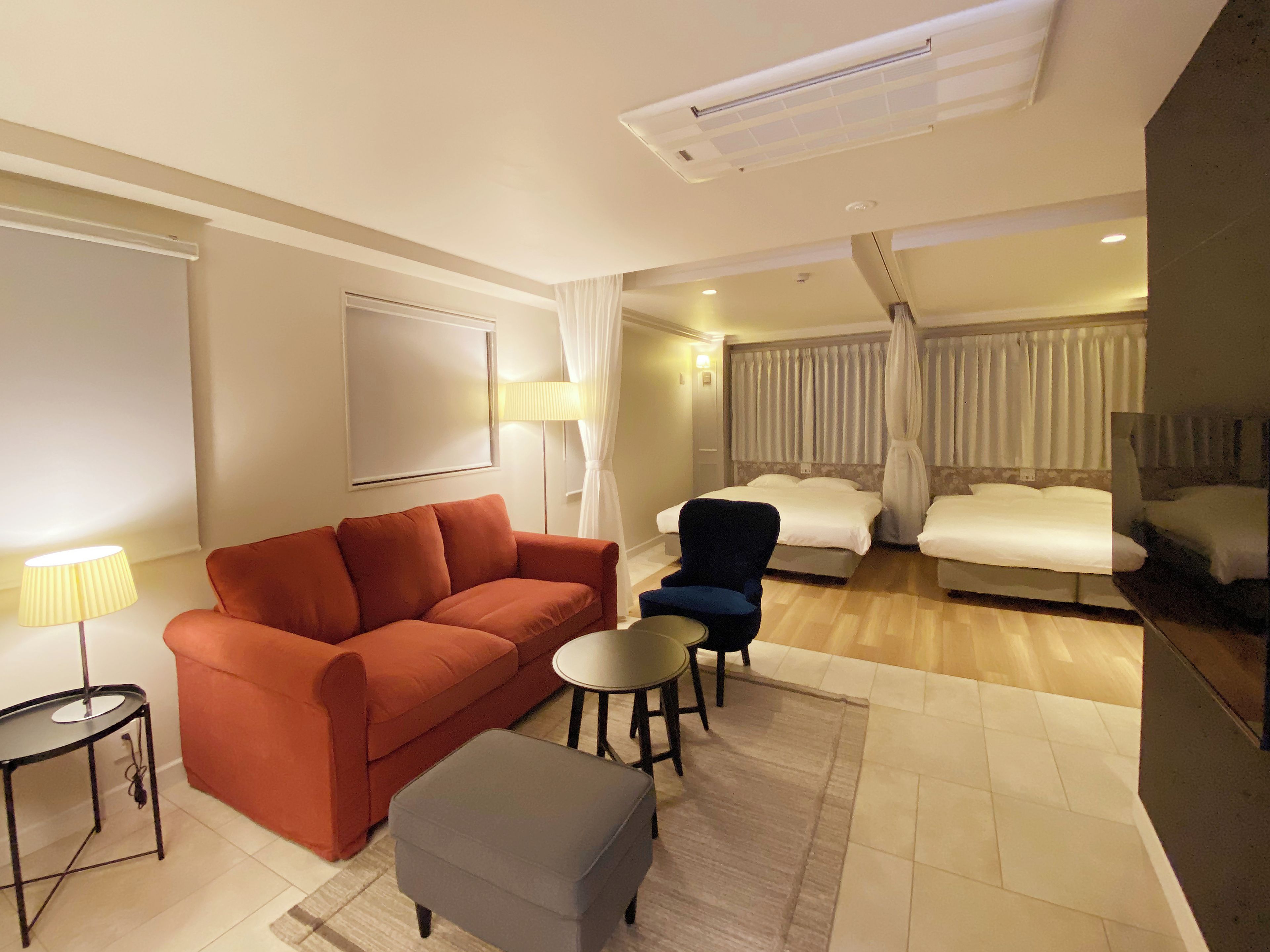 Habitación de hotel con sofá, sillón, reposapiés y una mesita.