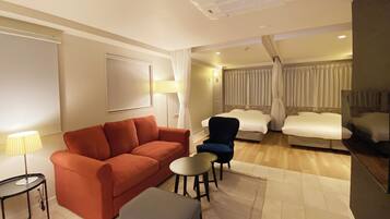Habitación de hotel con sofá, sillón, reposapiés y una mesita.