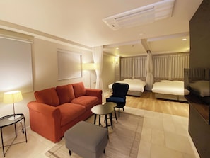 Habitación de hotel con sofá, sillón, reposapiés y una mesita.