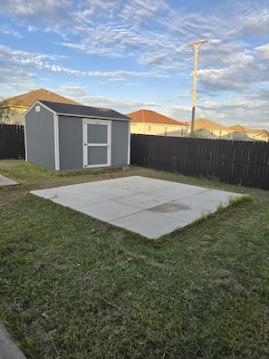 A backyard with a shed, a wooden fence, and a paved area. - 3-bedroom house Oasis of calm, in safe neighborhood of Killeen. Airport area. (Killeen)