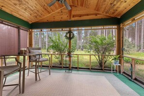 Un intérieur en bois avec une table et des chaises, de grandes fenêtres et une vue sur une forêt.