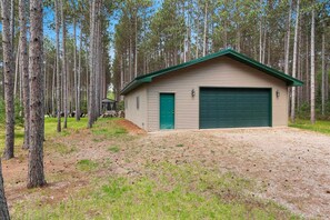 Un bâtiment d’un seul étage, doté d’un toit végétalisé et d’une porte de garage, entouré d’une forêt.