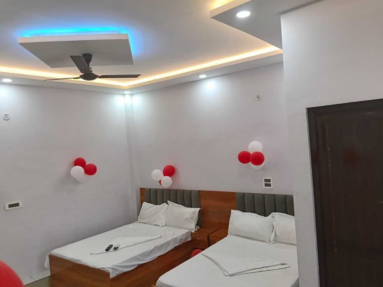 A hotel room with two beds, a ceiling fan, recessed lighting, and decorative balloons.