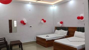 A hotel room with two beds, a ceiling fan, and red and white balloons.