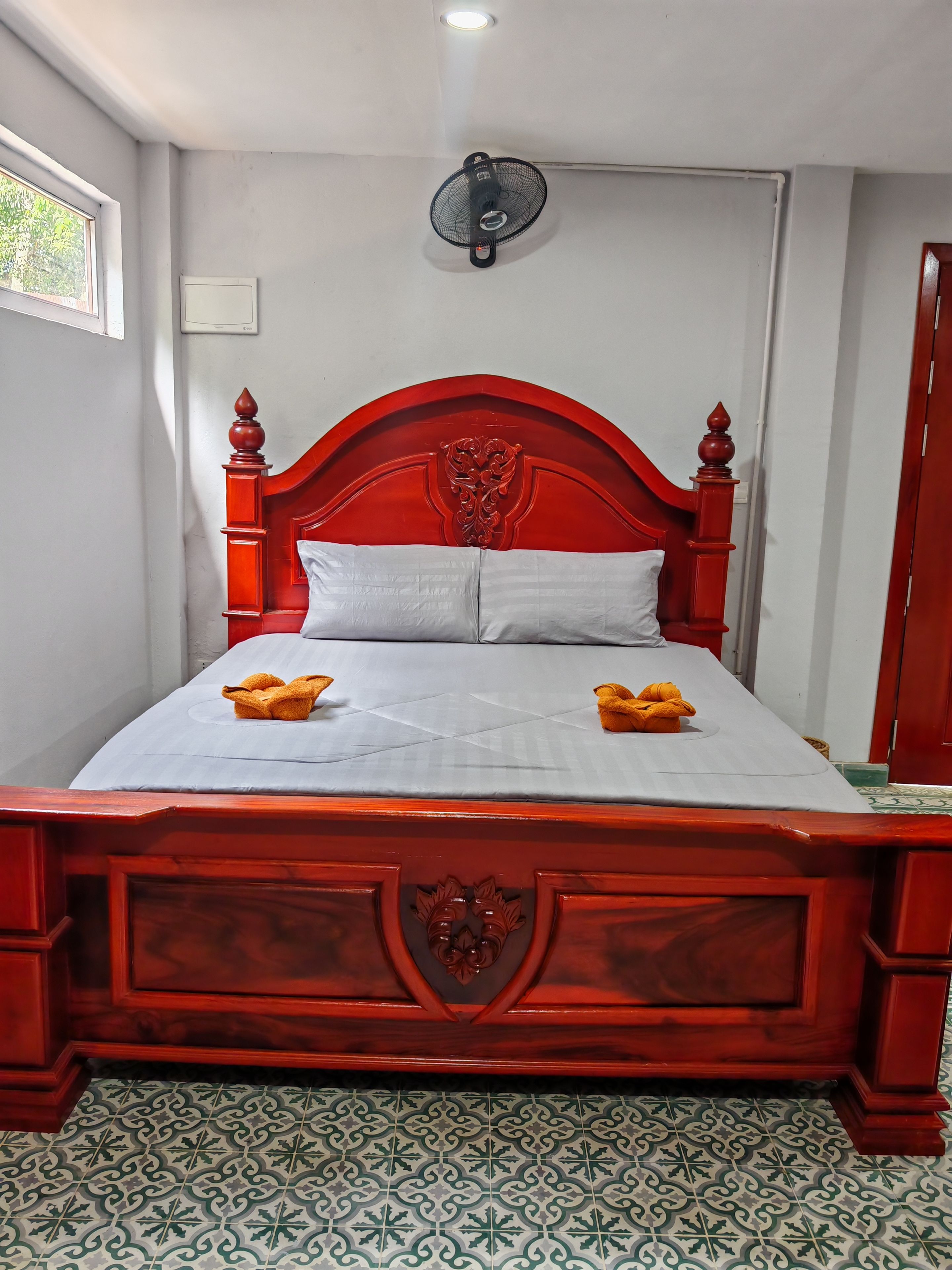 A bed with a red headboard, white bedding, and two folded towels.