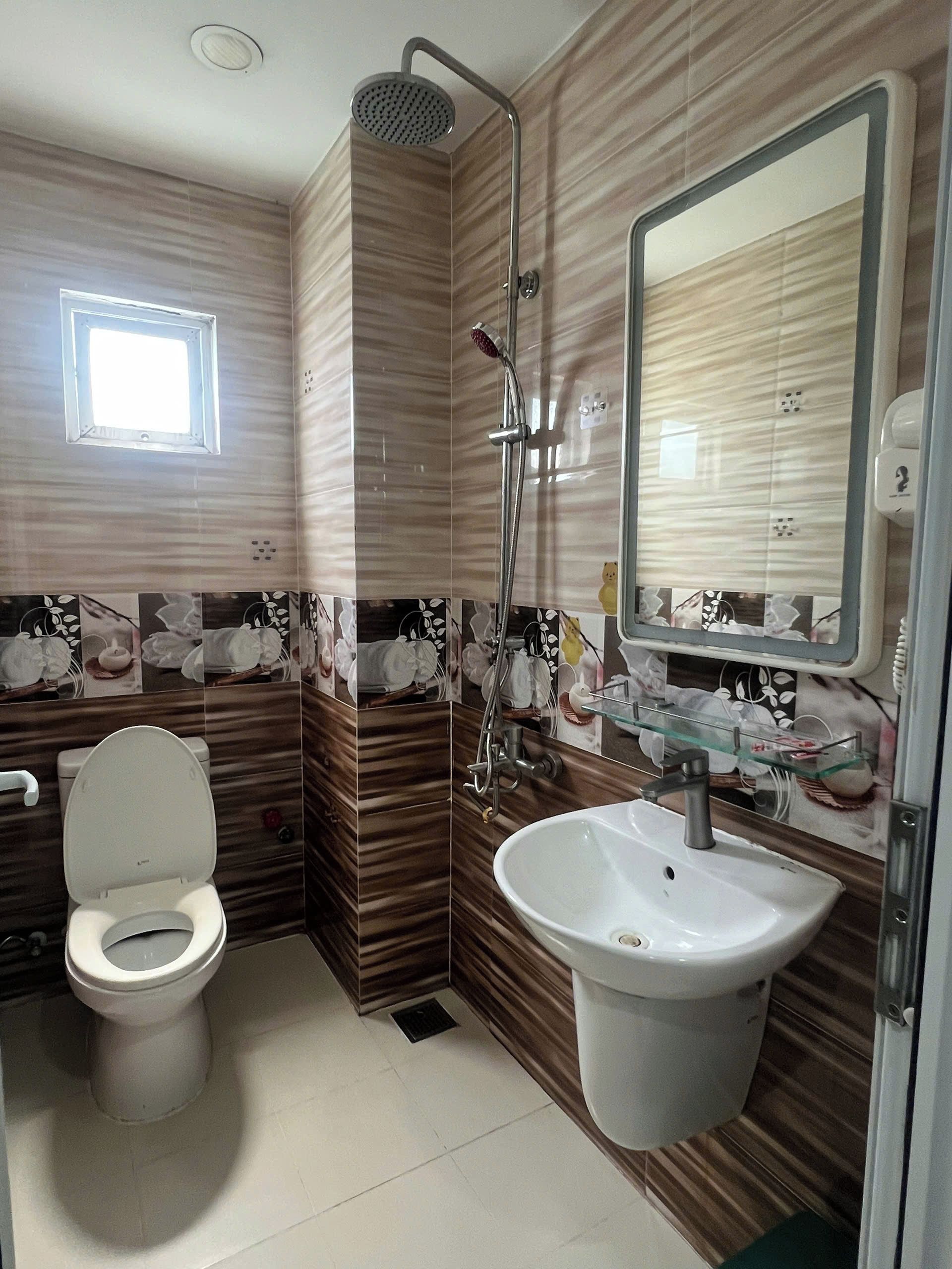 Un baño con inodoro, lavabo, ducha y ventana.
