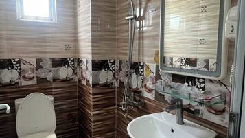 Un baño con inodoro, lavabo, ducha y ventana.