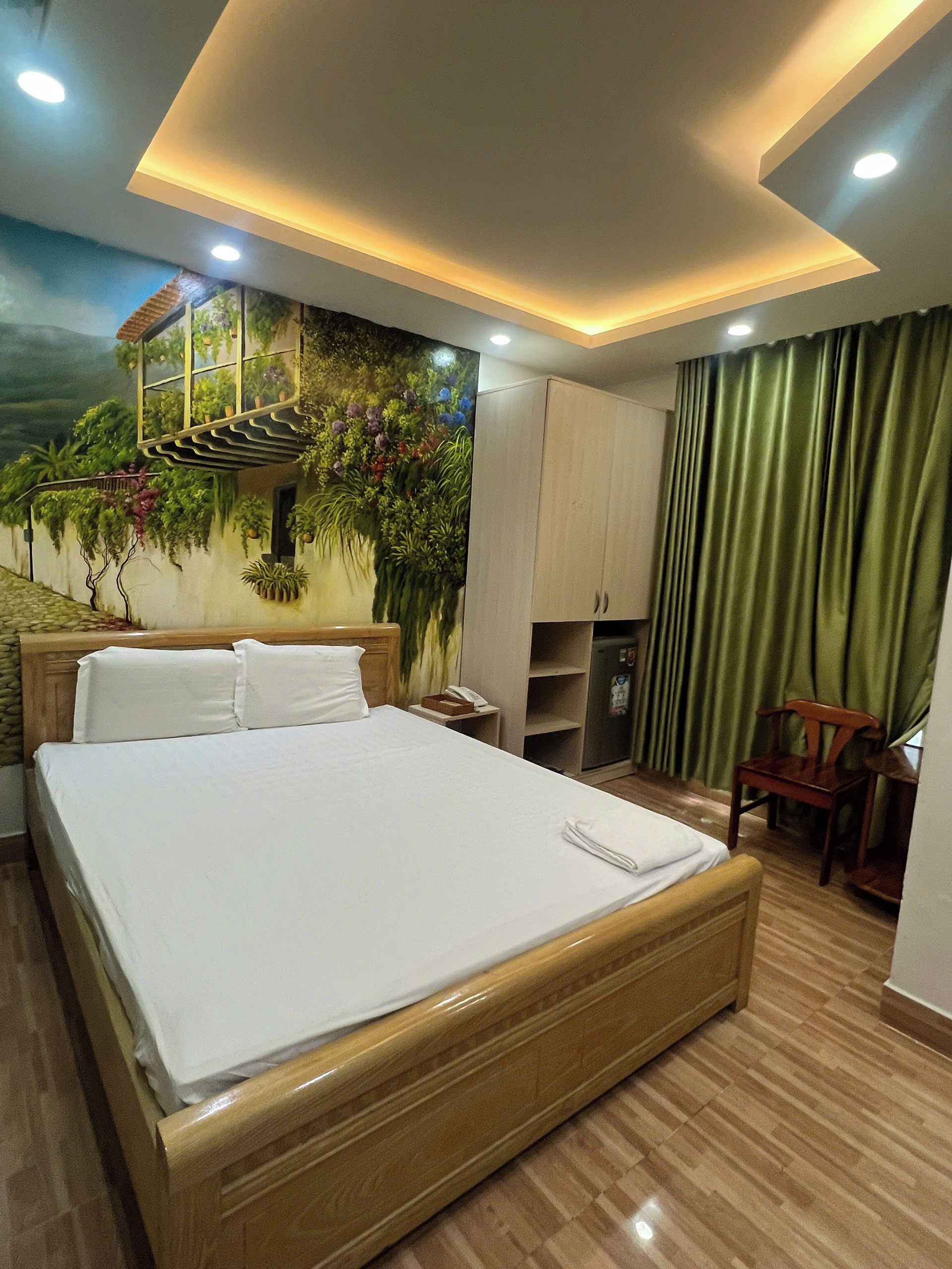 Habitación de hotel con cama, escritorio, silla, armario y un mural en la pared.