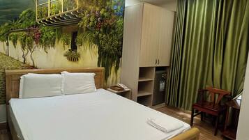 Habitación de hotel con cama, escritorio, silla, armario y un mural en la pared.