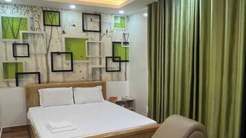 Habitación de hotel moderna con una cama de madera, un sillón y una pared decorada con cuadros y plantas.