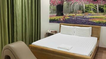 Habitación de hotel con cama, sofá curvo, mesita de noche con teléfono y un gran mural floral en la pared.