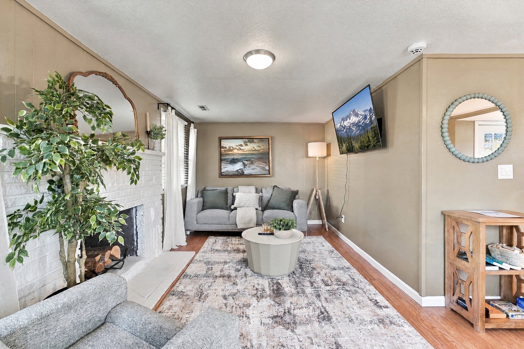 A living room with a fireplace, a sofa, a coffee table, and a TV mounted on the wall.