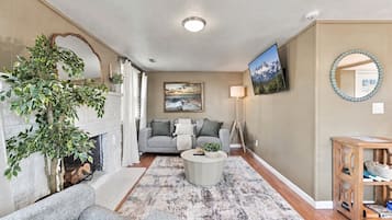 A living room with a fireplace, a sofa, a coffee table, and a TV mounted on the wall.