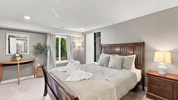 A modern bedroom with a large bed, bedside tables, a mirror, and a window with curtains.