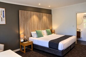 Une chambre d’hôtel moderne avec un grand lit, une table de chevet avec une lampe et une petite table d’appoint.