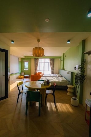 A room with a bed, a dining table with chairs, a hanging light fixture, and a potted plant. - Lot 78 (Malacca City)