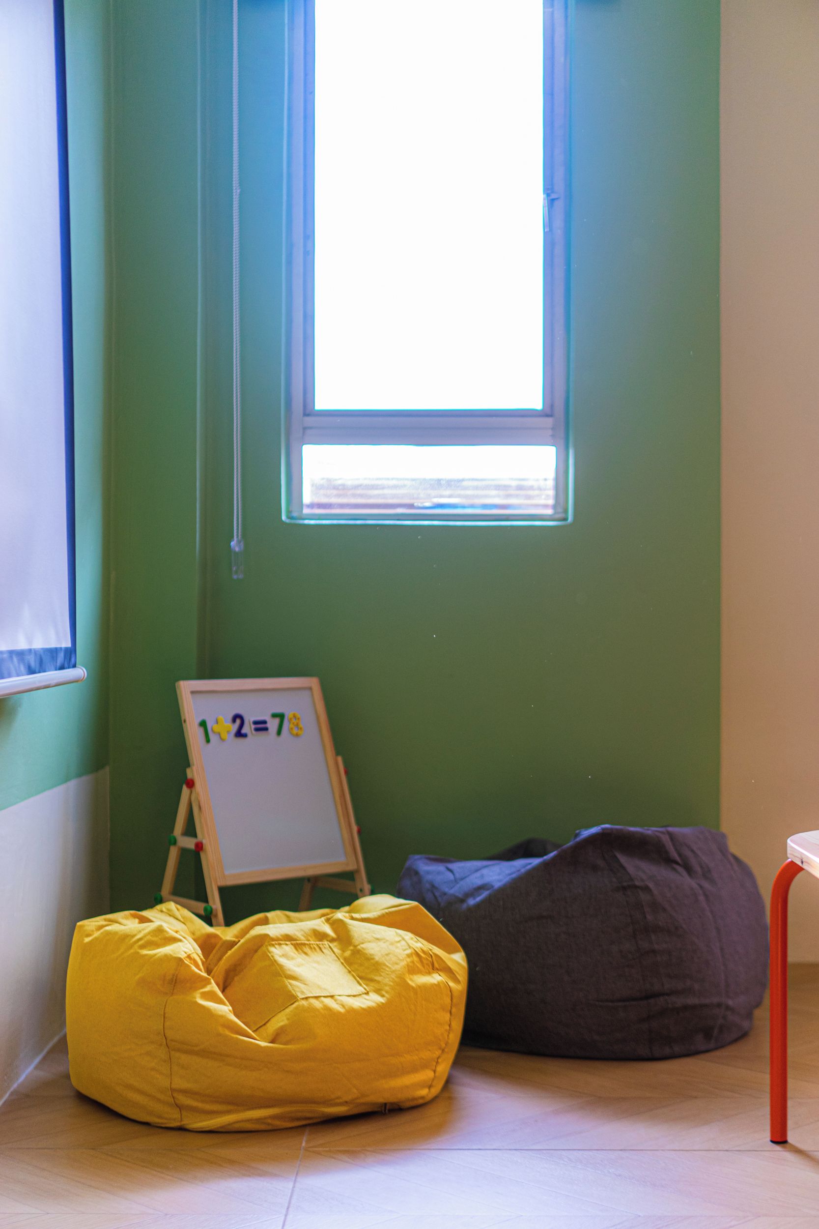 A room with a window, a whiteboard with a math equation, a yellow bean bag, and a dark bean bag.