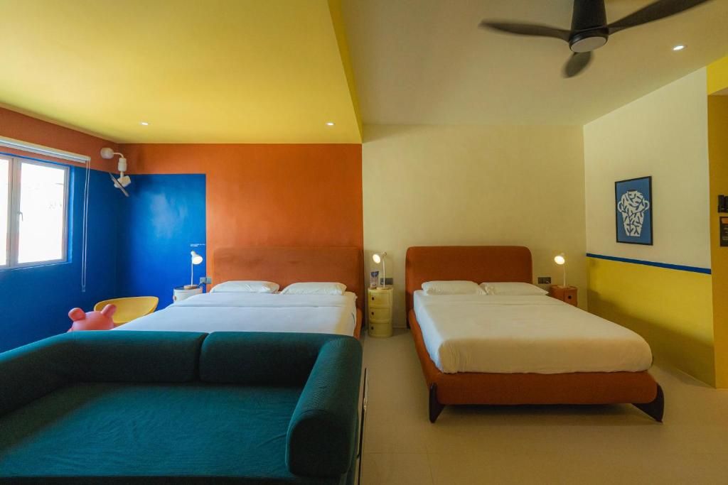 A hotel room with two beds, a ceiling fan, and a window.