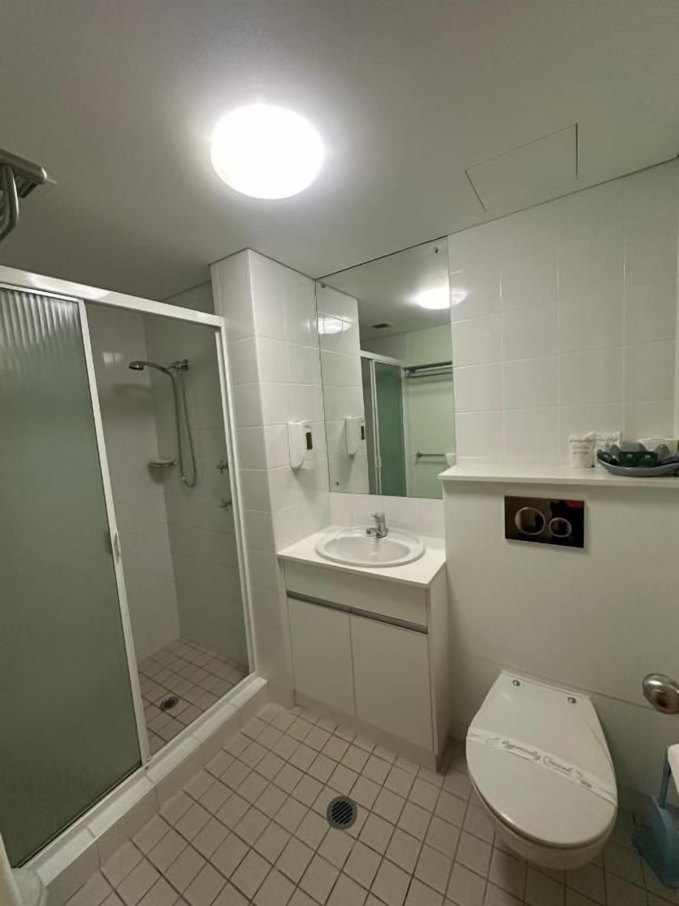 A bathroom with a shower, toilet, sink, and mirror.