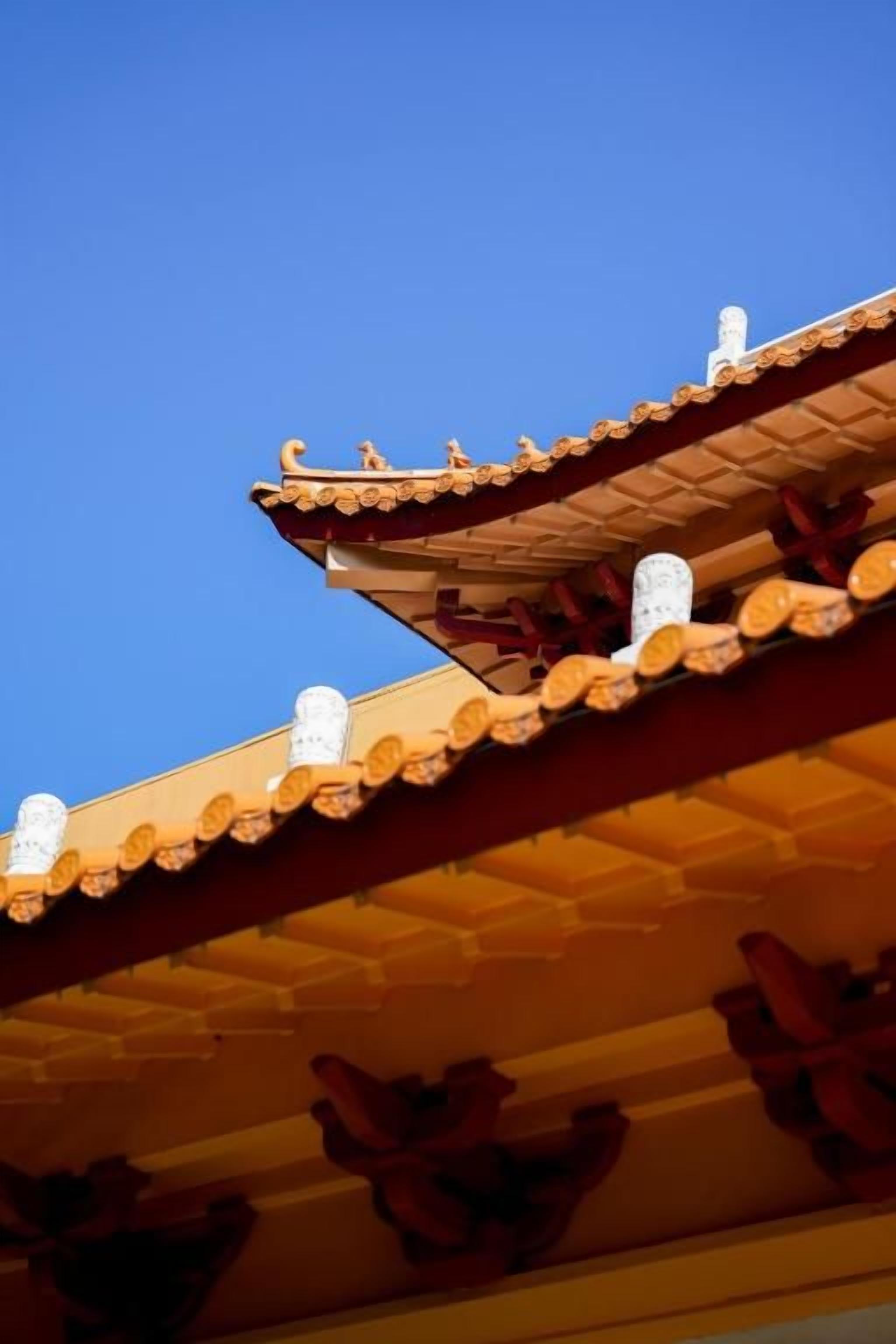 A traditional roof with decorative elements and a clear blue sky in the background.