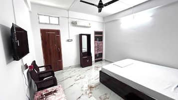 A bedroom with a bed, a television, a wardrobe, and a ceiling fan.