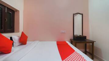 A bedroom with a bed, pillows, a bedside table, a mirror, and a red and white patterned runner.