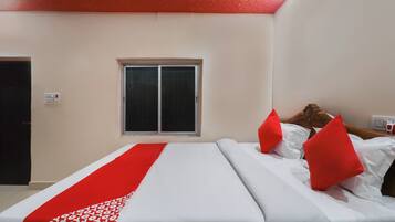 A hotel room with a bed, a window, and a door.