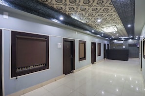 A hallway with closed doors, a reception desk, and patterned ceiling.