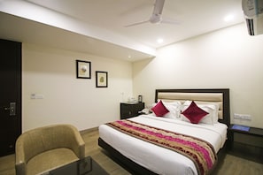 A hotel room with a bed, a chair, a nightstand, and a ceiling fan. - Hotel O Central Palace (Dehradun)