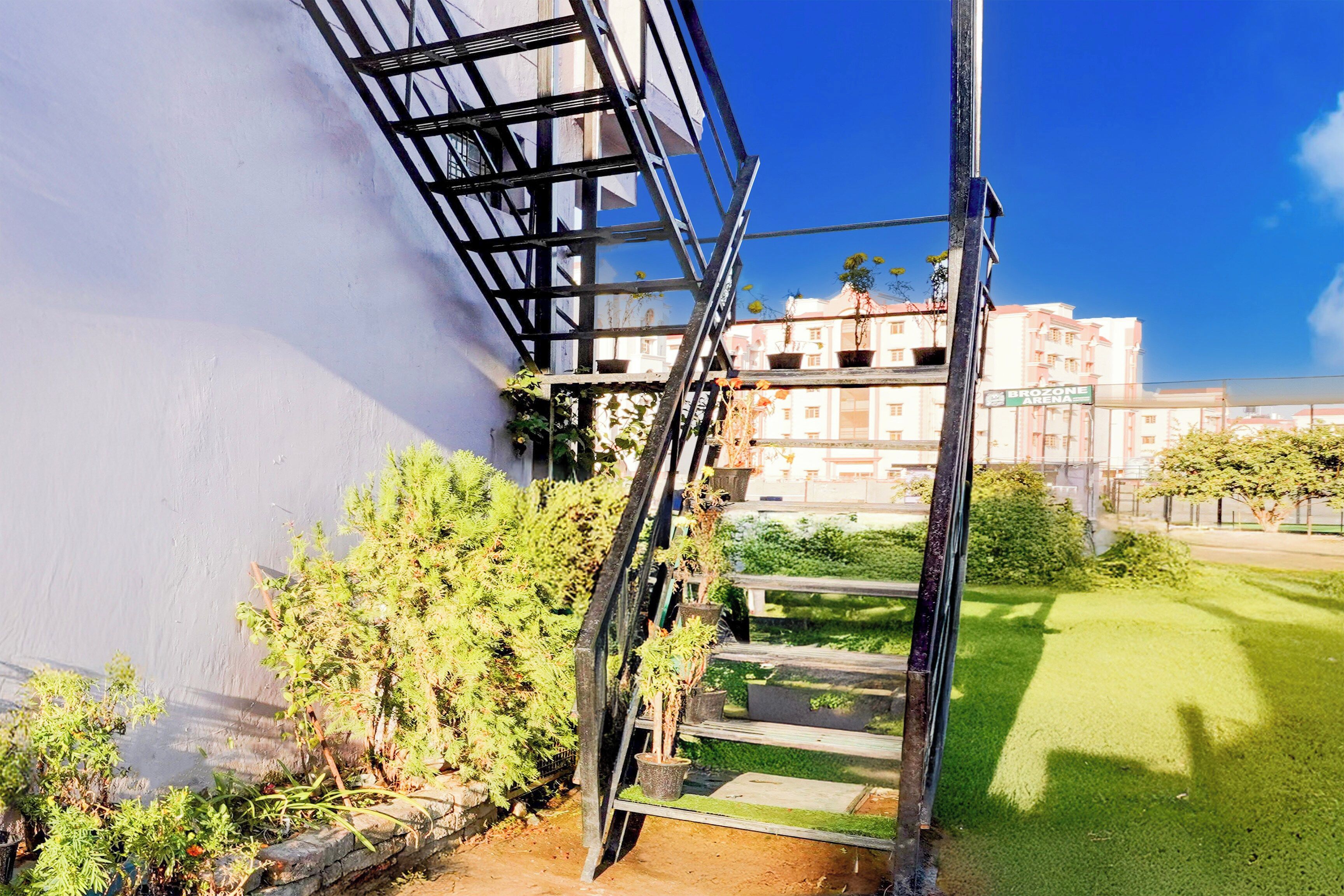 A staircase leading to a balcony with a view of a building and a grassy area.