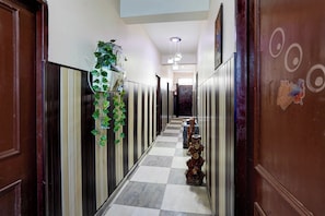 A hallway with a checkered floor, wooden doors, and a wall-mounted water dispenser. - Hotel O Govind Guest house (Dehradun)
