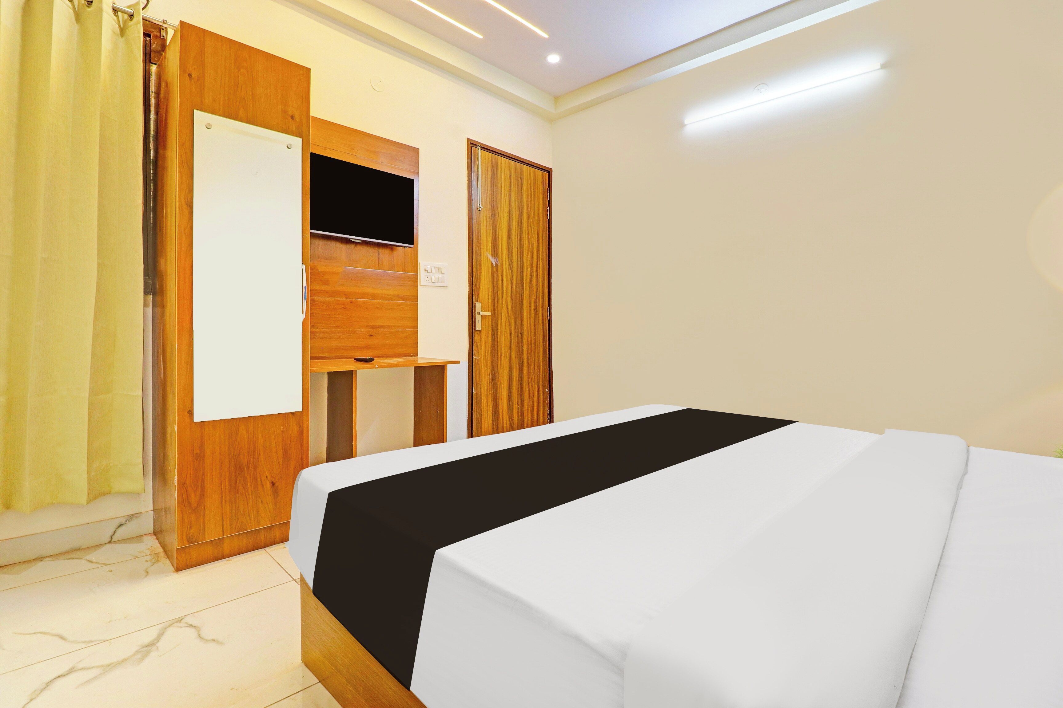 Ein Hotelzimmer mit einem Bett, einem Holzschrank, einem Fernseher und einem Vorhang.
