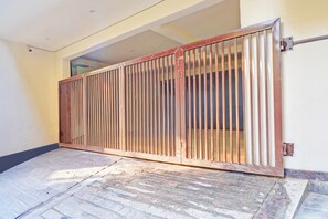 Una entrada tancada amb barres verticals, un sòl de rajoles i una paret amb una llum d'accentuació encastrada.