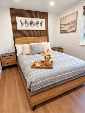 Quarto com estrutura de cama de madeira, cabeceira com design de painel vertical e mesa de cabeceira com gaveta.